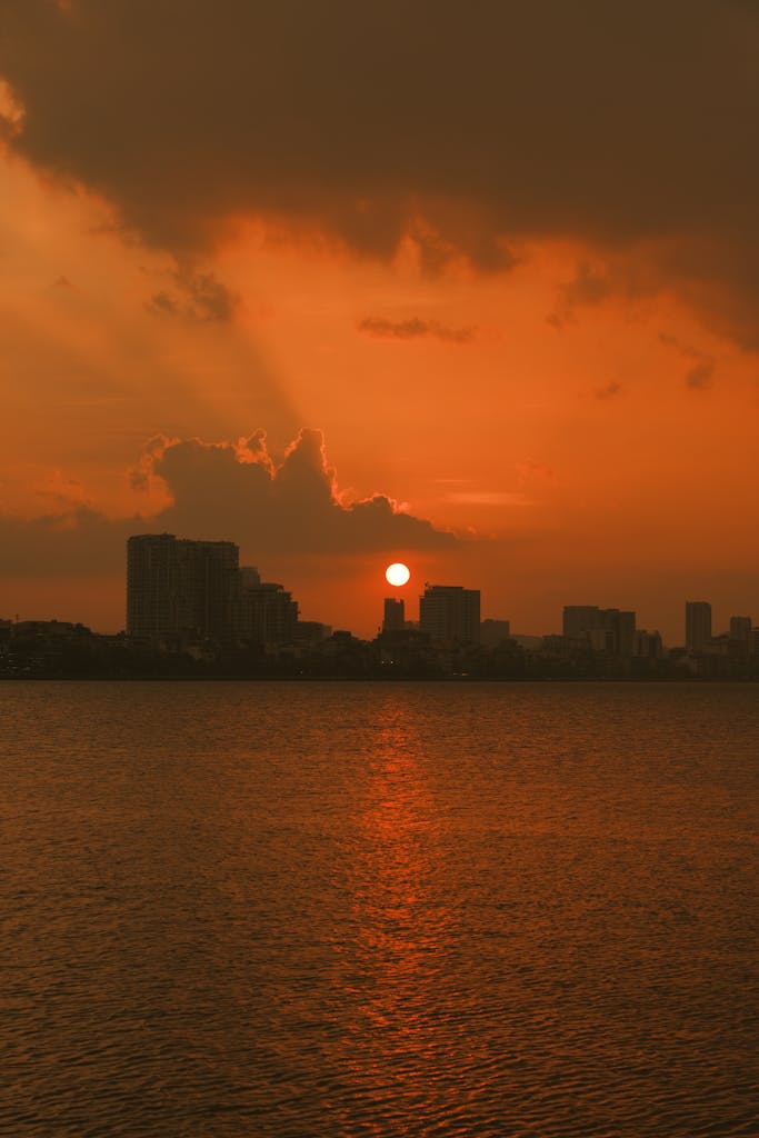Breathtaking autumn sunset over the Hanoi skyline with orange skies and city silhouette.