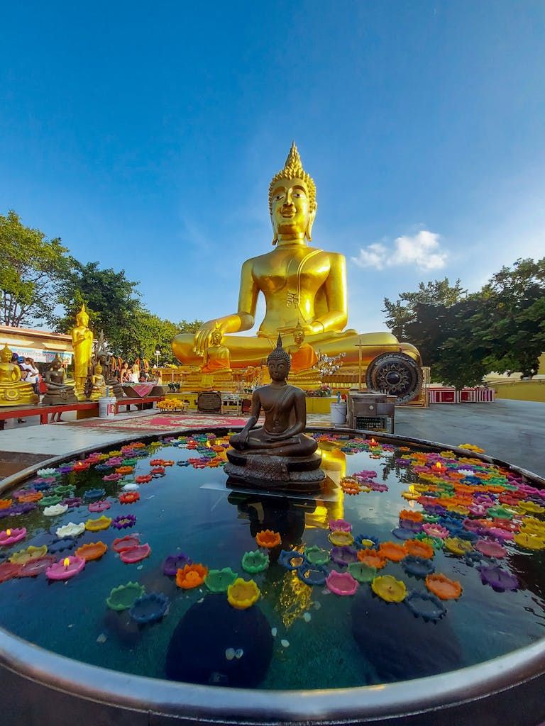 Captivating view of the golden Buddha statue at Wat Phra Yai temple in Pattaya, Thailand, under a clear blue sky.