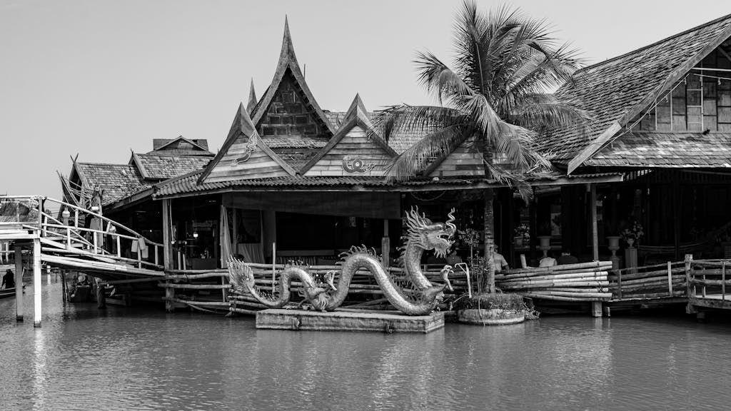 Explore the traditional Thai architecture and dragon statue at Pattaya Floating Market in black and white.