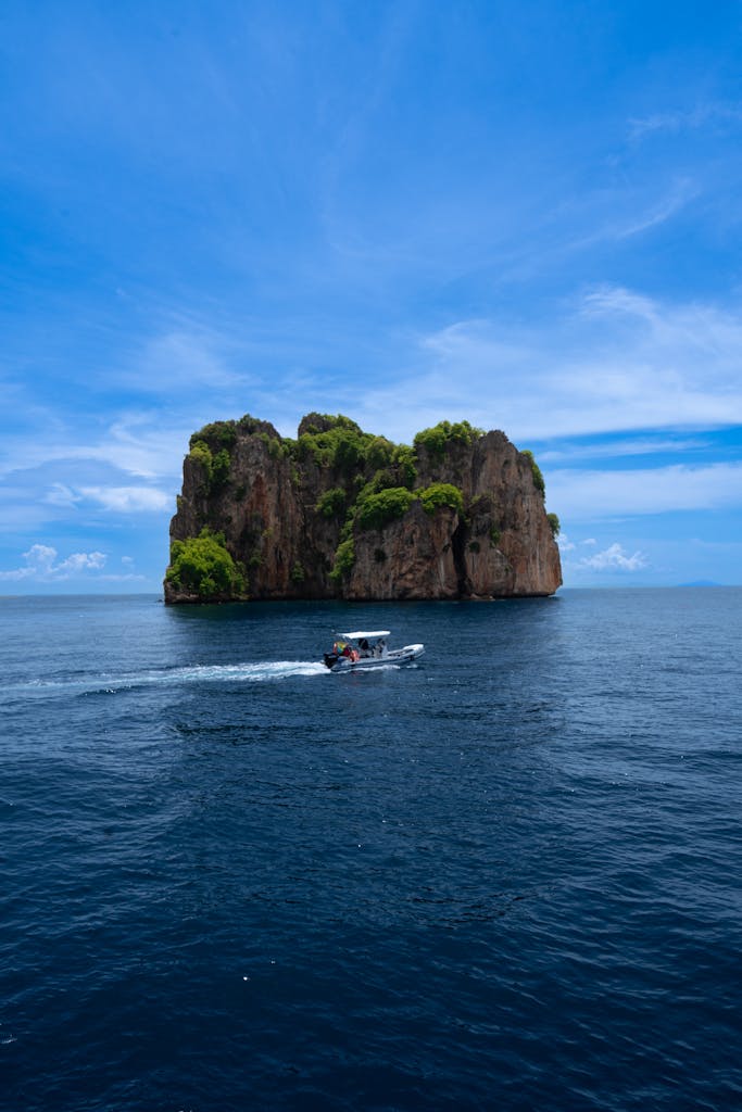 Limestone cliffs in Krabi, Thailand with a boat on the clear blue sea under a vibrant sky.