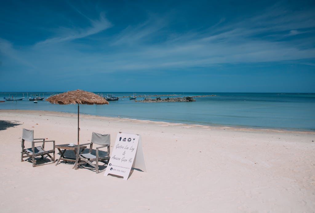 Relaxing beach view on Koh Samui with chairs and parasol under the sunny sky.