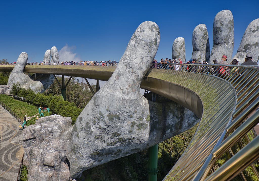 The iconic Golden Bridge with giant hand sculptures at Ba Na Hills, Vietnam, under a clear blue sky.