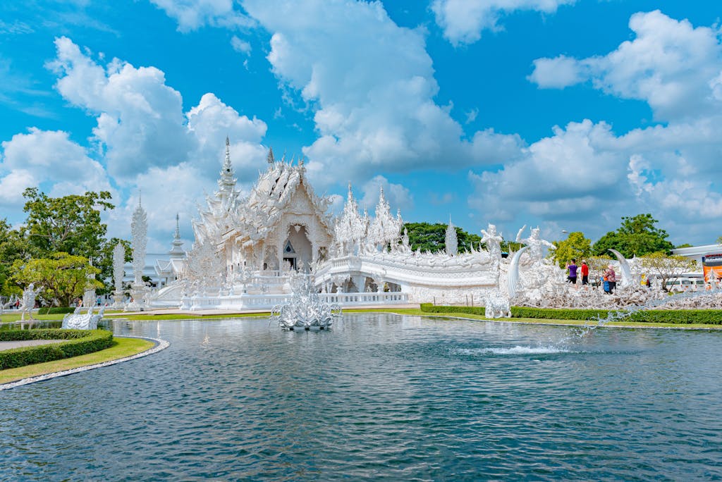 The iconic White Temple in Thailand captured on a sunny day with clear reflections.