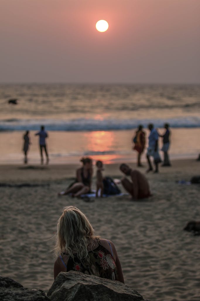 Tourists relaxing on Varkala Beach in India during a beautiful sunset.