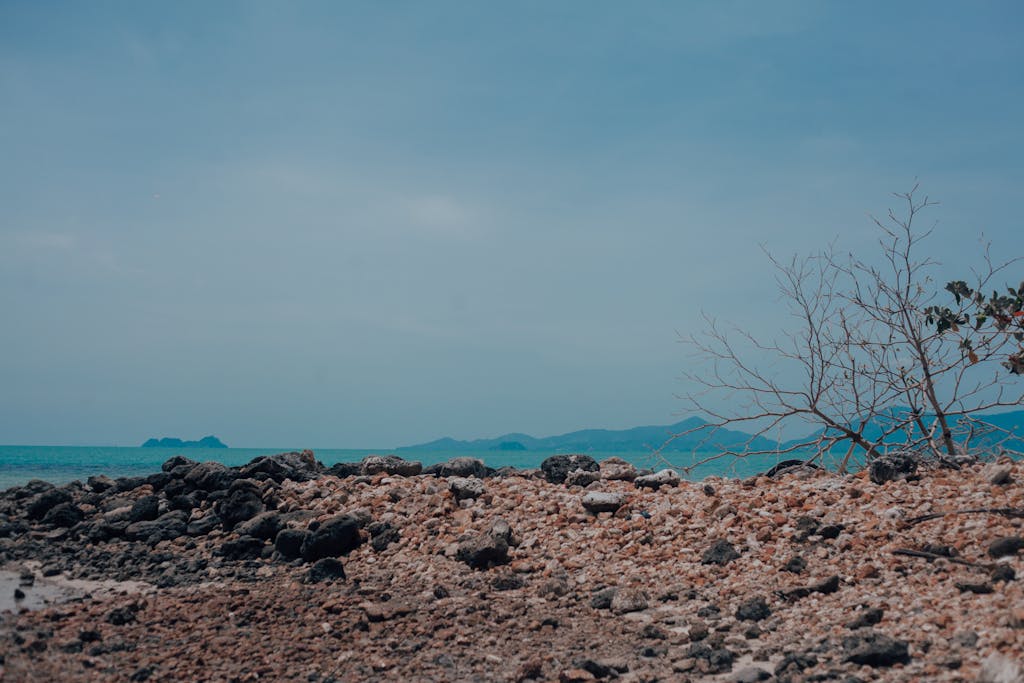 Tranquil view of a rocky beach with a backdrop of the turquoise sea and distant islands on Koh Samui, Thailand.
