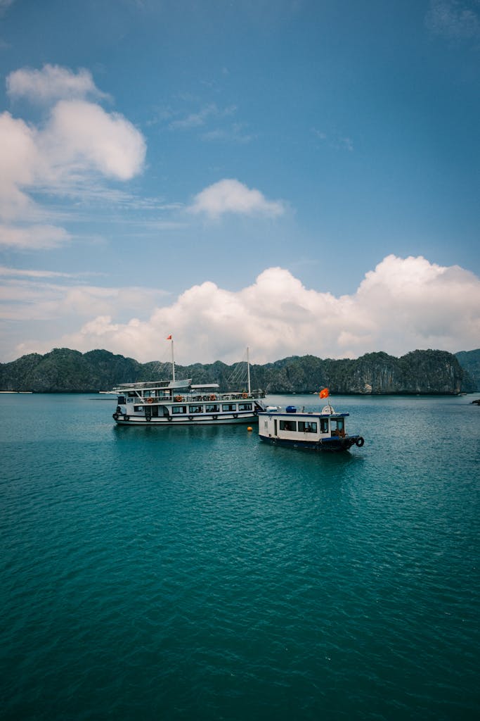 Two boats float on Ha Long Bay's turquoise waters, surrounded by scenic limestone islets.