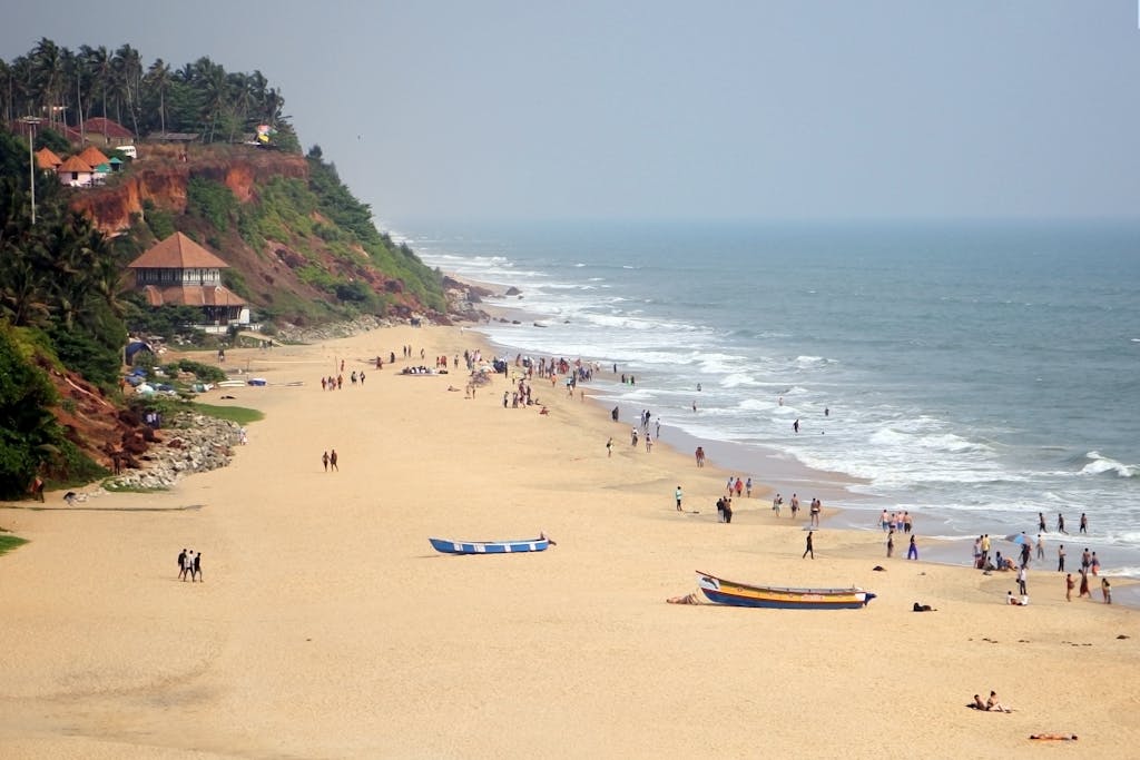 Varkala Beach with cliffs, boats, and people enjoying the sunny day by the sea.