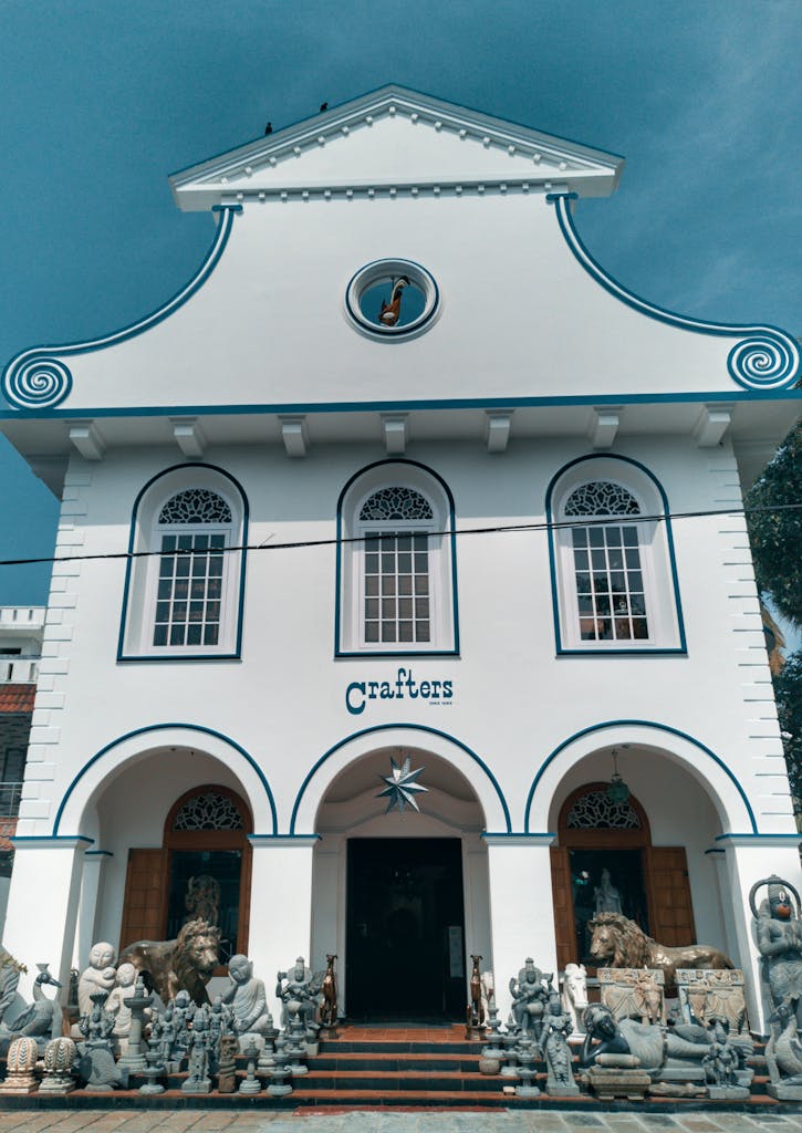 White colonial-style building with stone sculptures in front, capturing artistic essence.