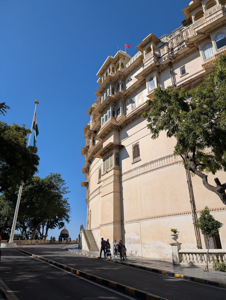 A beautiful view of the City Palace in Udaipur, showcasing its architecture and surroundings under a clear blue sky.