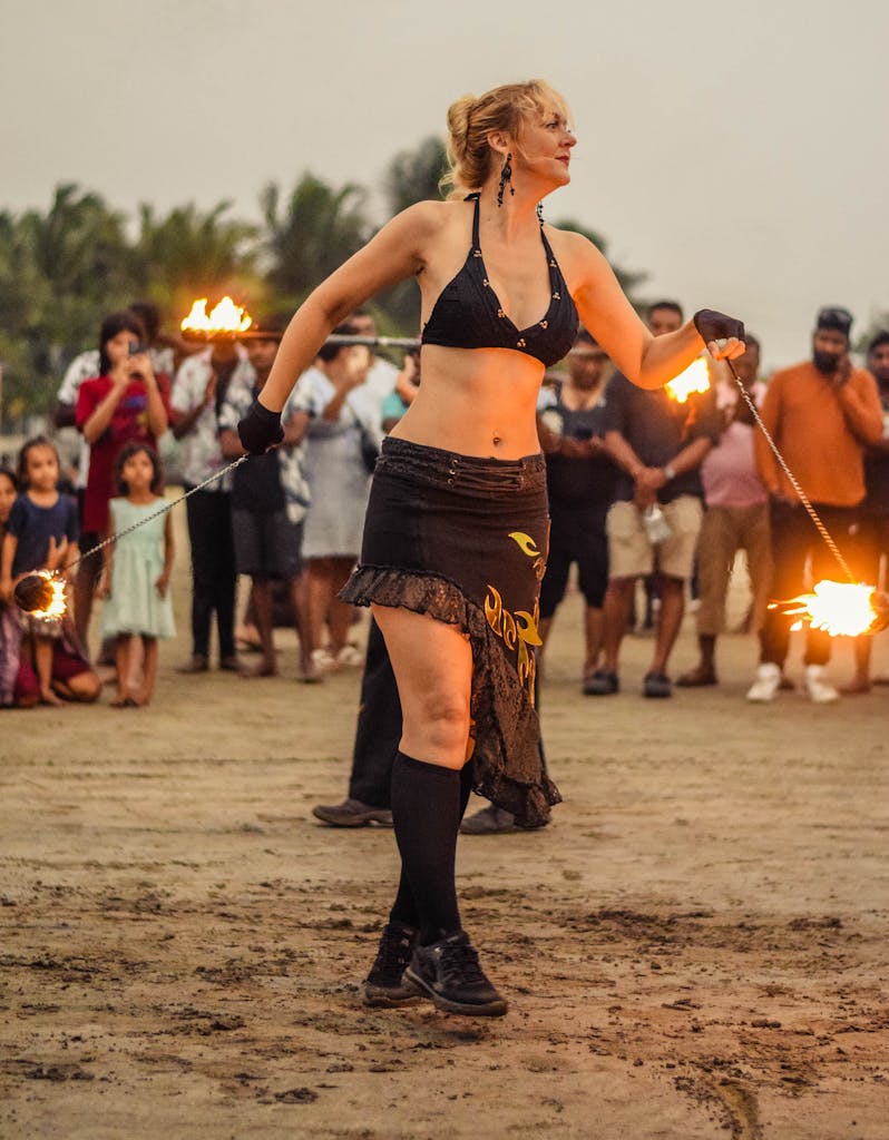 A fire performer captivates a large crowd at sunset on Arambol Beach in Goa, India.