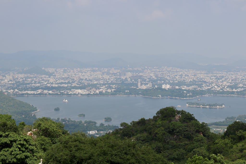 A stunning view of Udaipur city and Lake Pichola surrounded by lush greenery.