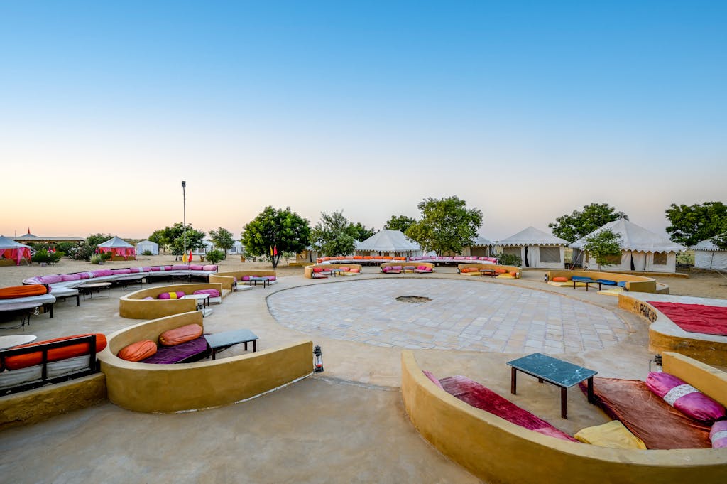 A vibrant desert camp with colorful seating and tents in Jaisalmer, India, under a clear sky.