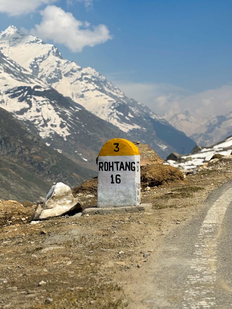 Mile marker indicating 16 km to Rohtang Pass in the Himalayan mountains near Manali, India.