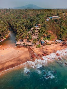 Scenic aerial view of a beach resort in Goa with lush greenery and vibrant water.
