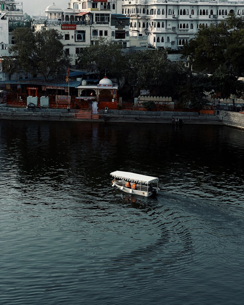 White boat navigating city lake surrounded by historic architecture.